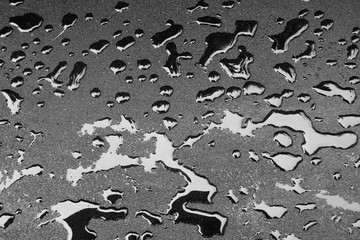 Dark drops of liquid on a hard surface. Fresh asphalt and fuel drops. Wet surface texture.