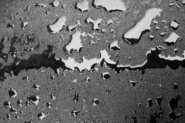 Dark drops of liquid on a hard surface. Fresh asphalt and fuel drops. Wet surface texture.