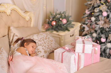 The girl sleeps on the bed with New Year's gifts