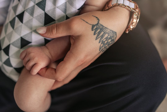 Young mother holding her adorable baby boy's hand