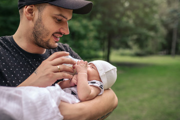Smiling father feeding his baby boy outside with a bottle