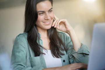 Portrait of stunning brunette smiling at her laptop