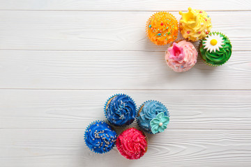 Composition with delicious colorful cupcakes on white wooden background