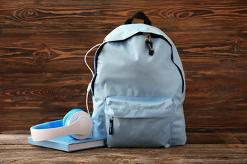 Backpack with school supplies on wooden table