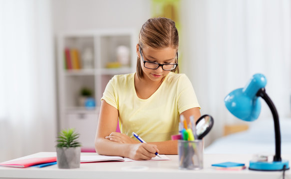 education and learning concept - student girl writing to notebook at home