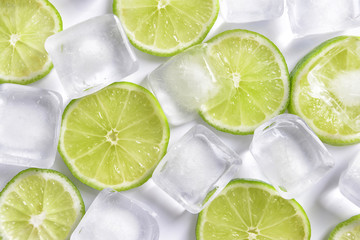 Fresh sliced ripe lime and ice cubes on white background