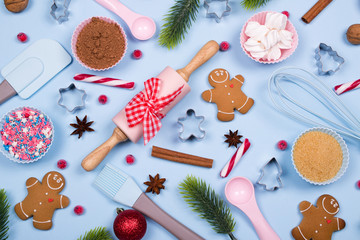 Baking Christmas cookies card. Christmas spices, cookie cutters, ingredients for christmas baking and kitchen utensils gingerbread cookies on blue pastel background