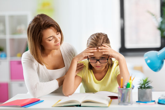 education, family and learning concept - mother helping daughter with difficult homework task at home