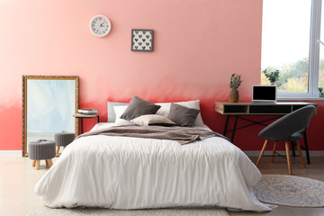 Interior of room with comfortable bed near pink wall