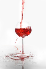 Pouring of red wine into glass on white background
