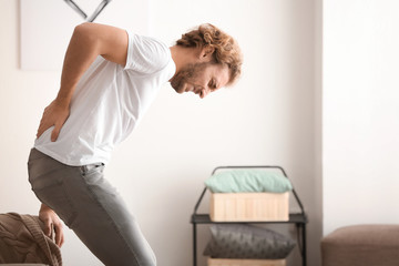 Young man suffering from back pain at home