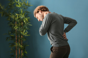 Young man suffering from back pain at home