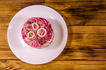 White plate with russian traditional new year salad herring under fur coat on wooden table. Top view