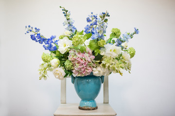 Delicate volumetric bouquet of flowers in a blue vase on a light background