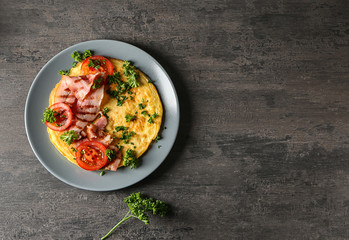 Plate with tasty omelet and bacon on grey table