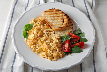 Plate with tasty omelet and toasted bread on white wooden table