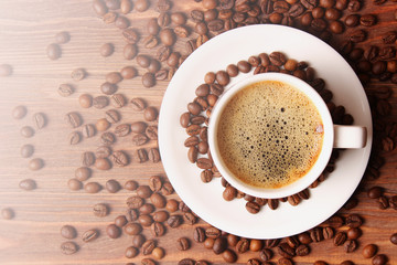 Cup of aromatic coffee and coffee beans on wooden background. Top view. Coffee drink