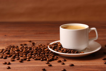 Cup of aromatic coffee and coffee beans on a wooden background.