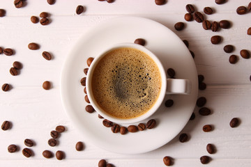 Cup of aromatic coffee and coffee beans on wooden background. Top view. Coffee drink