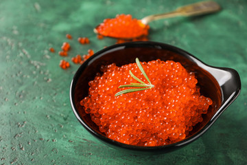 Bowl with delicious red caviar on color table