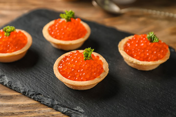 Delicious canapes with red caviar on slate plate