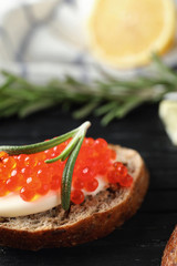 Delicious sandwich with red caviar on wooden board, closeup