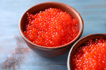 Bowls with delicious red caviar on color wooden table