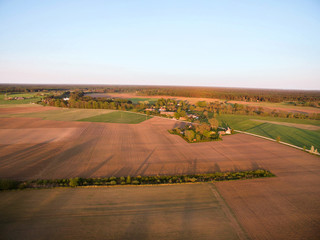 Fototapeta na wymiar Aerial drone view of old farmhouses, barns, houses and trees during sunset. Calm, peaceful landscape of countryside. Concept of agriculture industry