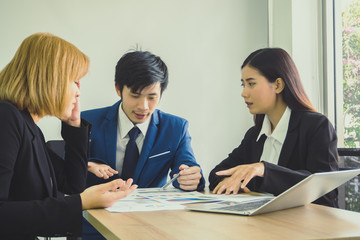 Businessman and woman communication together for work and pointing graph on wooden desk at office. Meeting concept.