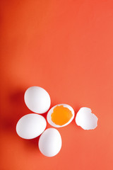 Cracked and whole chicken eggs on color background