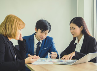 Businessman and woman communication together for work and pointing graph on wooden desk at office. Meeting concept.