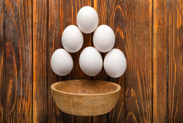 Composition with chicken eggs and bowl on wooden background