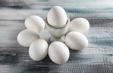 Holder with raw chicken eggs on wooden table