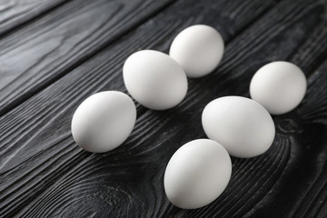 Raw chicken eggs on dark wooden background