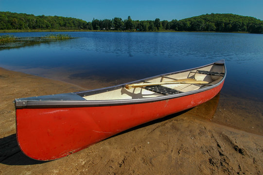 Large red canoe onshore of  lake