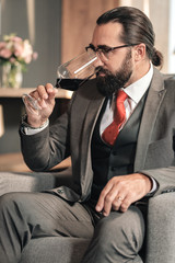 Bearded husband drinking some red wine while waiting for wife