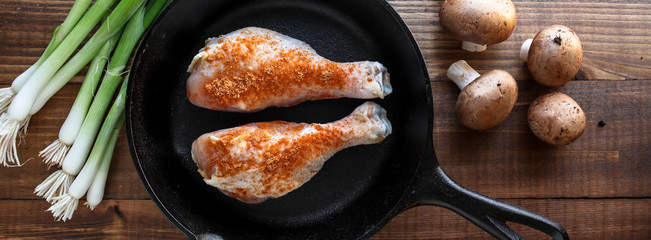 Chicken, scallions and mushrooms  on baking pan with wooden background