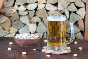 Mug of light beer on the table against the background of firewood.