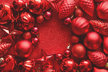 Red Christmas frame. Christmas balls, stars, cones and hearts on red sparkles background. Flat lay. Top view. Copy space. Toned
