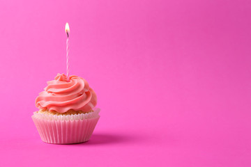 Tasty cupcake with burning candle on color background