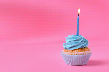Tasty cupcake with burning candle on color background