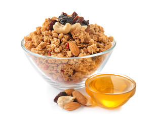 Granola with dried fruits and nuts in bowl and sweet honey on white background
