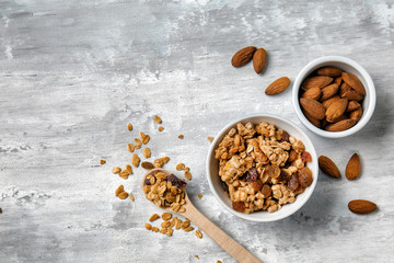 Granola with raisins and almonds in bowls on grey background