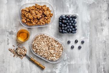 Oatmeal with granola, blueberries and sweet honey on grey background
