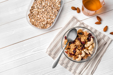 Granola in bowl and sweet honey on white wooden table