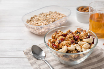Granola with dried fruits and nuts in bowl on white wooden table