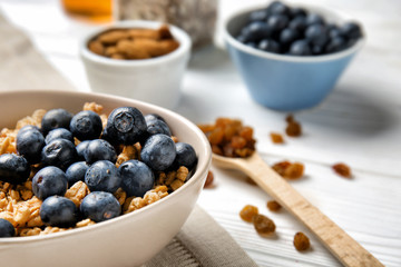 Granola with blueberries in bowl on white table