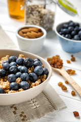 Granola with blueberries in bowl on white table