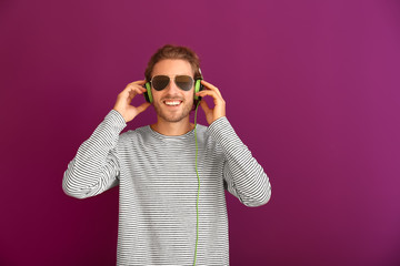 Young man listening to music on color background