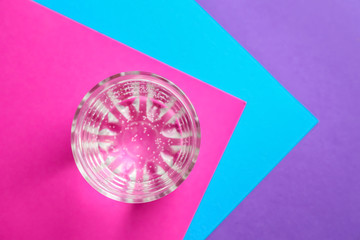 Glass of fresh water on color table